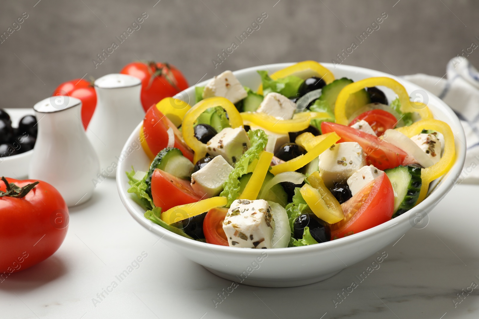 Photo of Delicious fresh Greek salad on white marble table, closeup