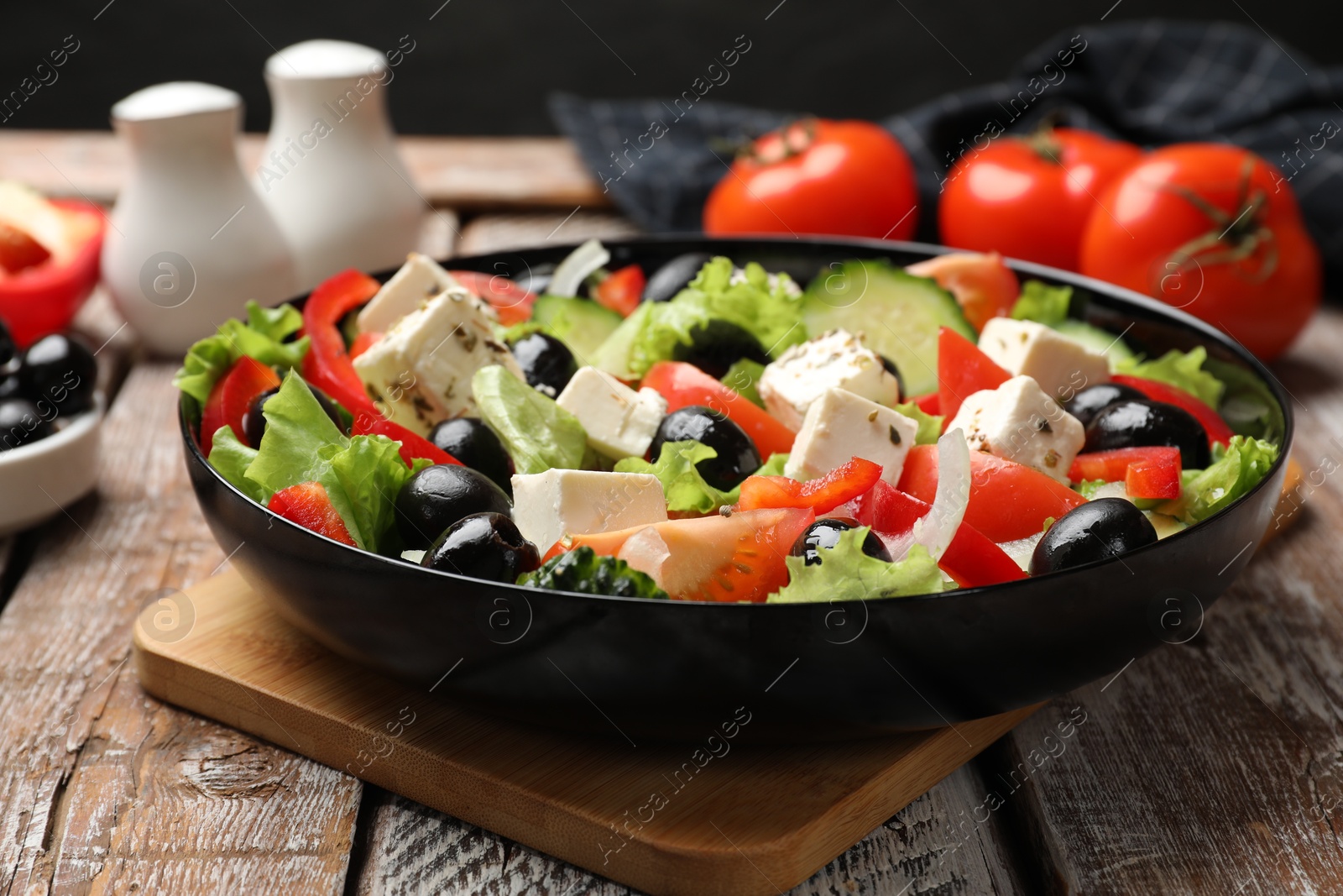 Photo of Delicious fresh Greek salad on wooden table, closeup