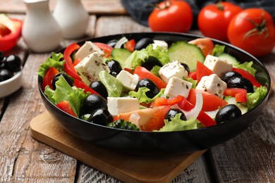 Photo of Delicious fresh Greek salad on wooden table, closeup