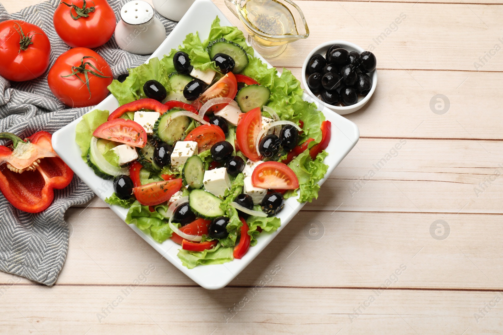 Photo of Delicious fresh Greek salad on white wooden table, flat lay