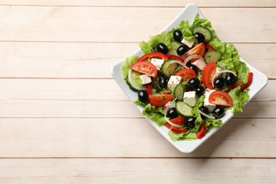 Photo of Delicious fresh Greek salad on white wooden table, top view. Space for text