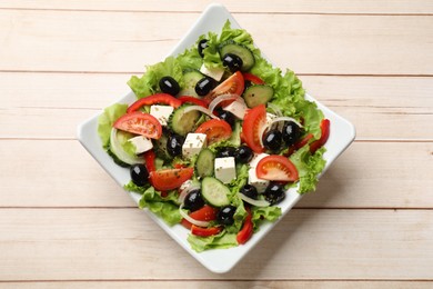 Photo of Delicious fresh Greek salad on white wooden table, top view