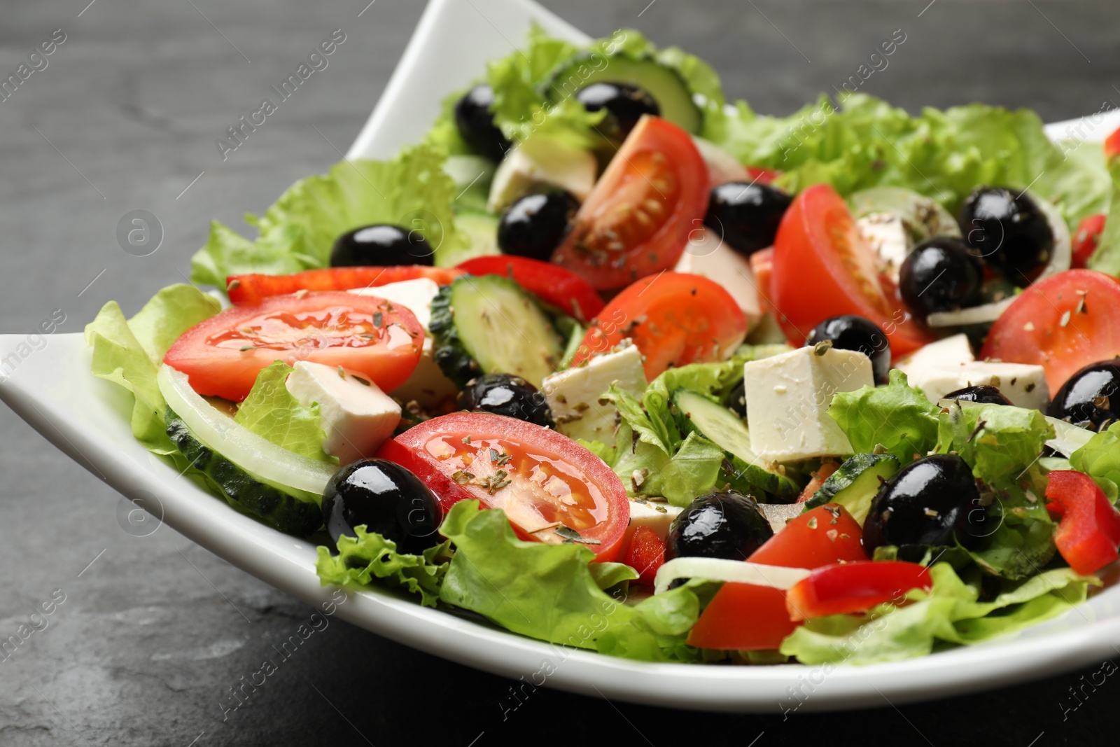 Photo of Delicious fresh Greek salad on black table, closeup