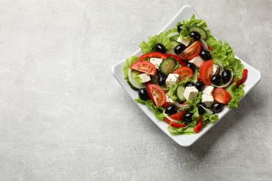 Photo of Delicious fresh Greek salad on grey table, top view. Space for text