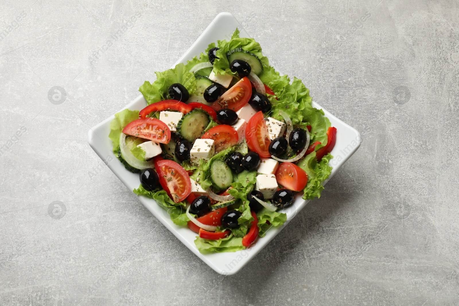 Photo of Delicious fresh Greek salad on grey table, top view