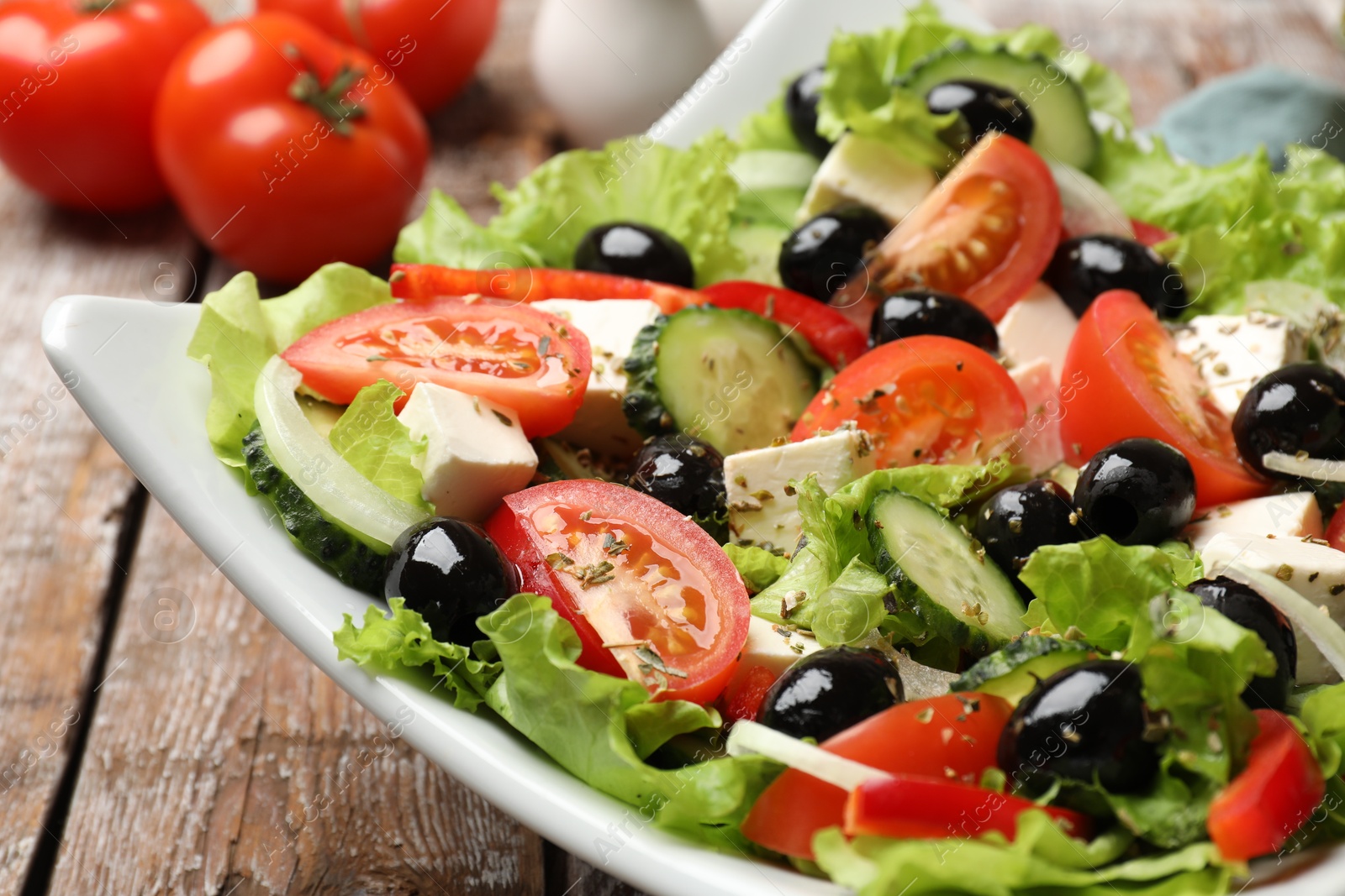 Photo of Delicious fresh Greek salad on wooden table, closeup