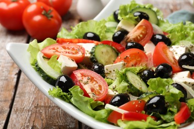 Photo of Delicious fresh Greek salad on wooden table, closeup