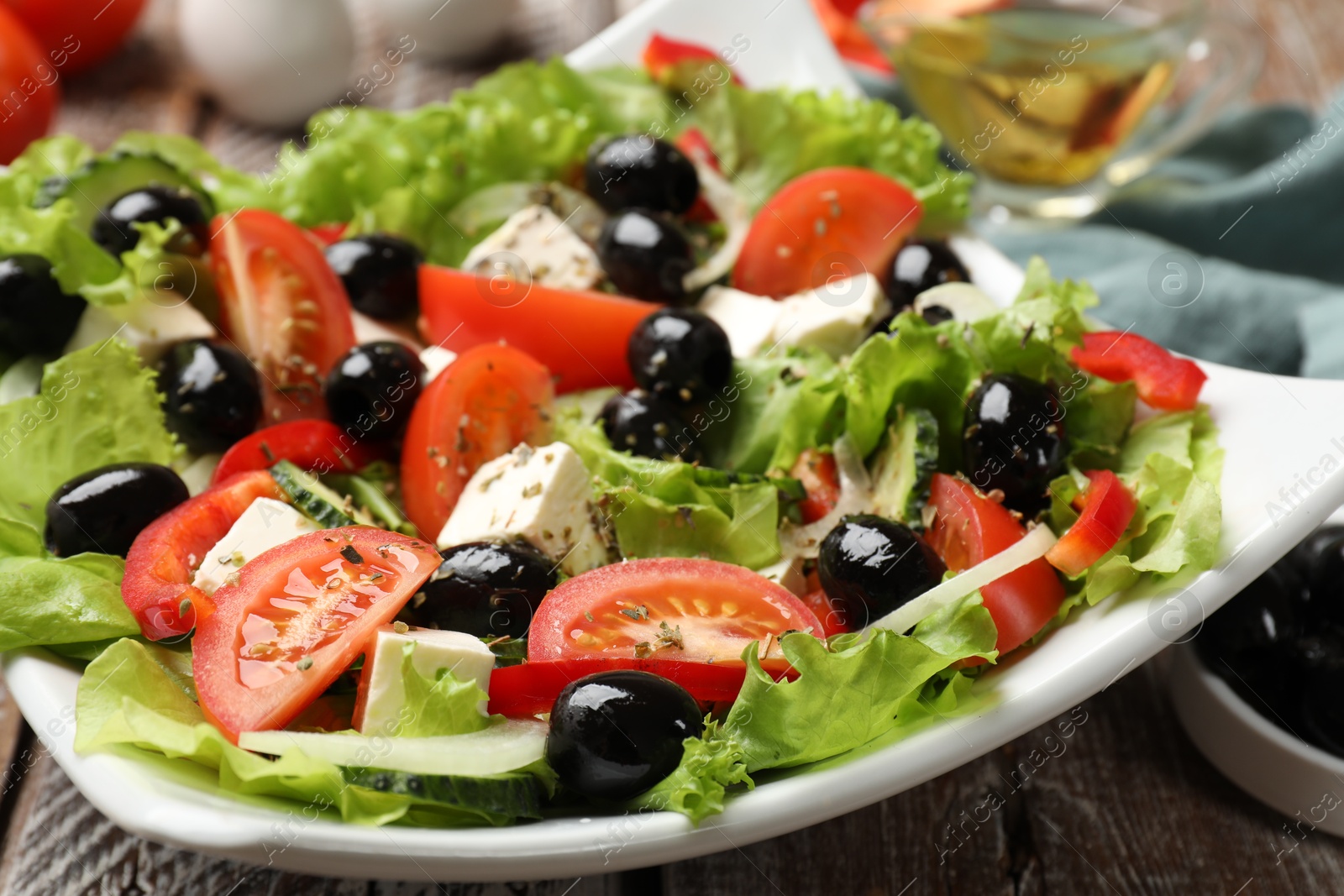 Photo of Delicious fresh Greek salad on wooden table, closeup