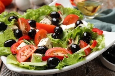 Photo of Delicious fresh Greek salad on wooden table, closeup