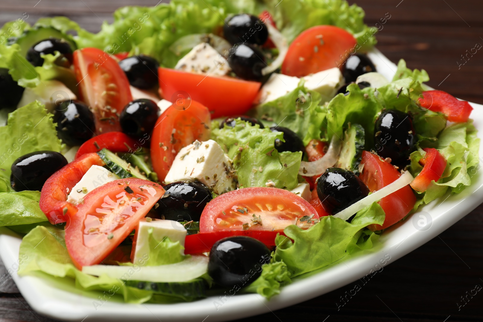 Photo of Delicious fresh Greek salad on wooden table, closeup