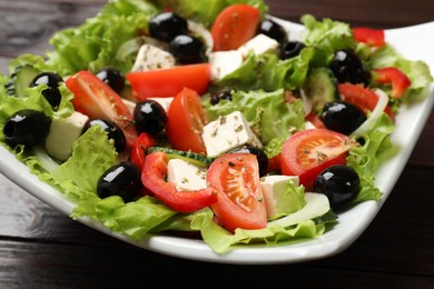 Photo of Delicious fresh Greek salad on wooden table, closeup