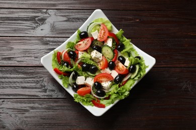 Photo of Delicious fresh Greek salad on wooden table, top view