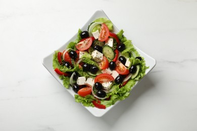 Photo of Delicious fresh Greek salad on white marble table, top view