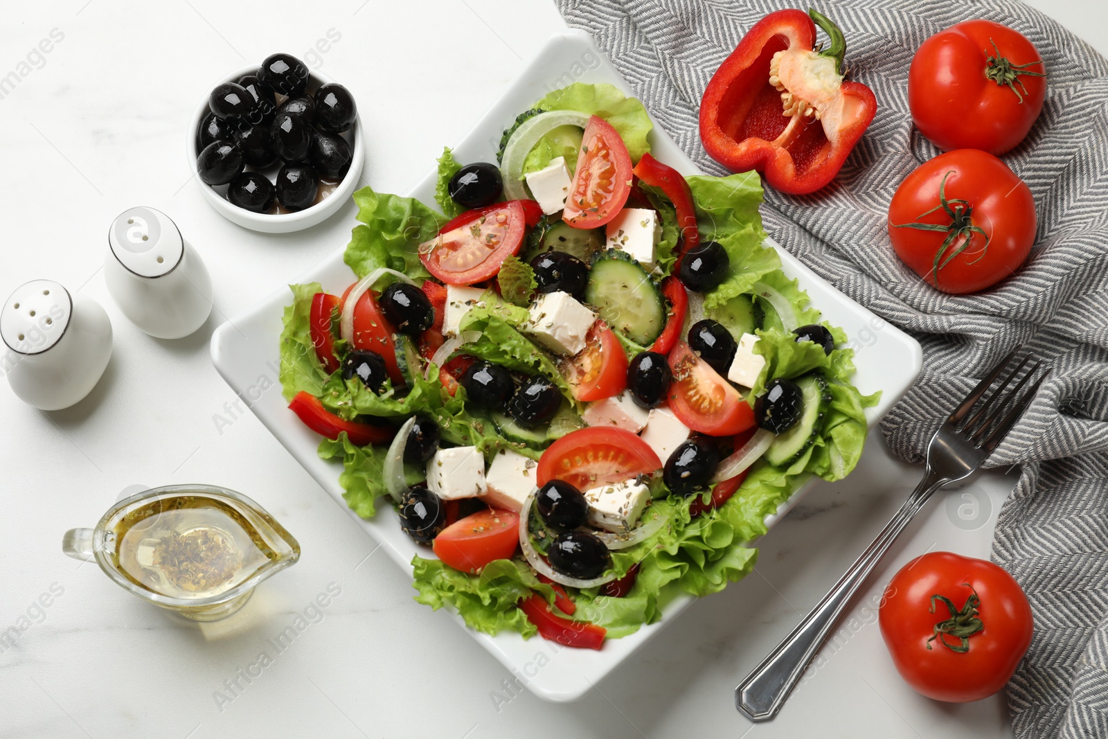 Photo of Delicious fresh Greek salad on white marble table, flat lay