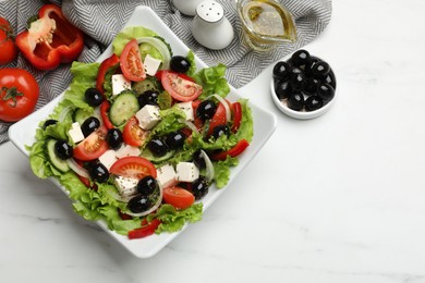 Photo of Delicious fresh Greek salad on white marble table, flat lay. Space for text