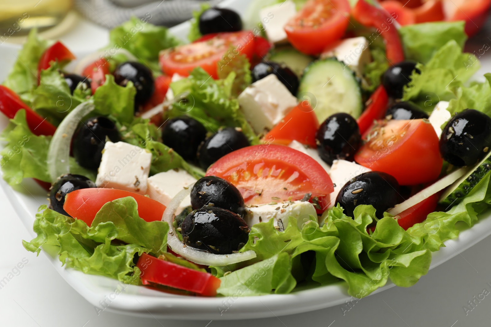 Photo of Delicious fresh Greek salad on white table, closeup