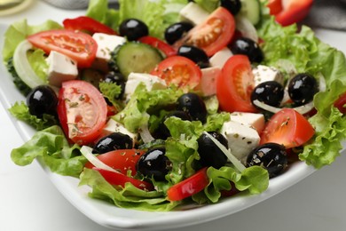 Photo of Delicious fresh Greek salad on white table, closeup