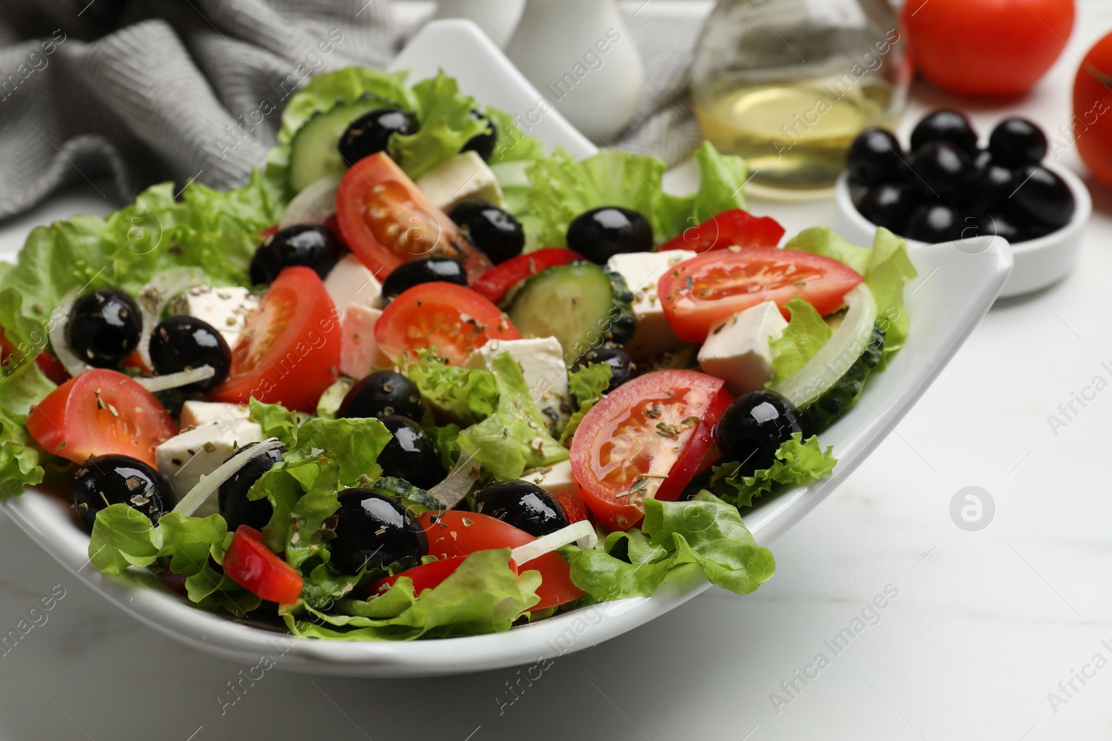 Photo of Delicious fresh Greek salad on white table, closeup