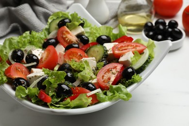 Photo of Delicious fresh Greek salad on white table, closeup