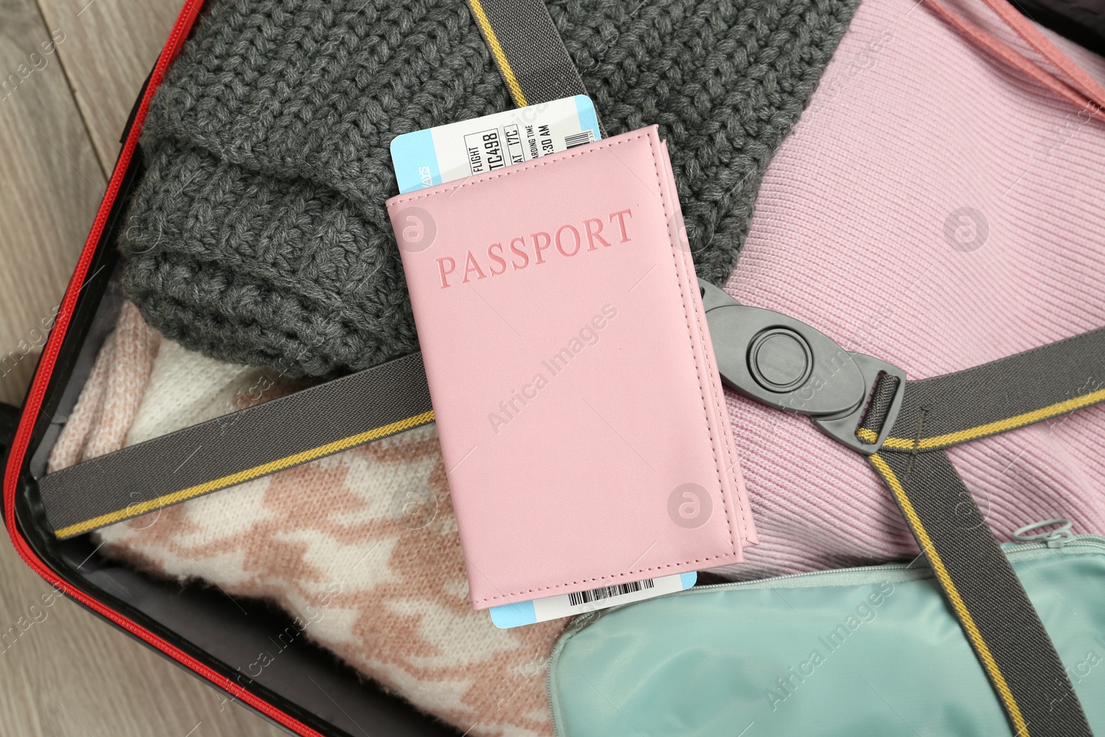 Photo of Passport with ticket on packed suitcase indoors, closeup