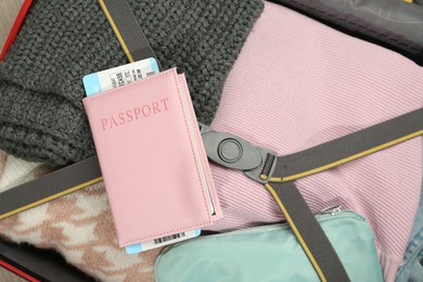 Photo of Passport with ticket on packed suitcase indoors, closeup