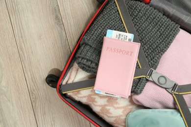 Photo of Passport with ticket on packed suitcase indoors, top view