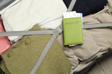 Photo of Passport with ticket on packed suitcase indoors, top view