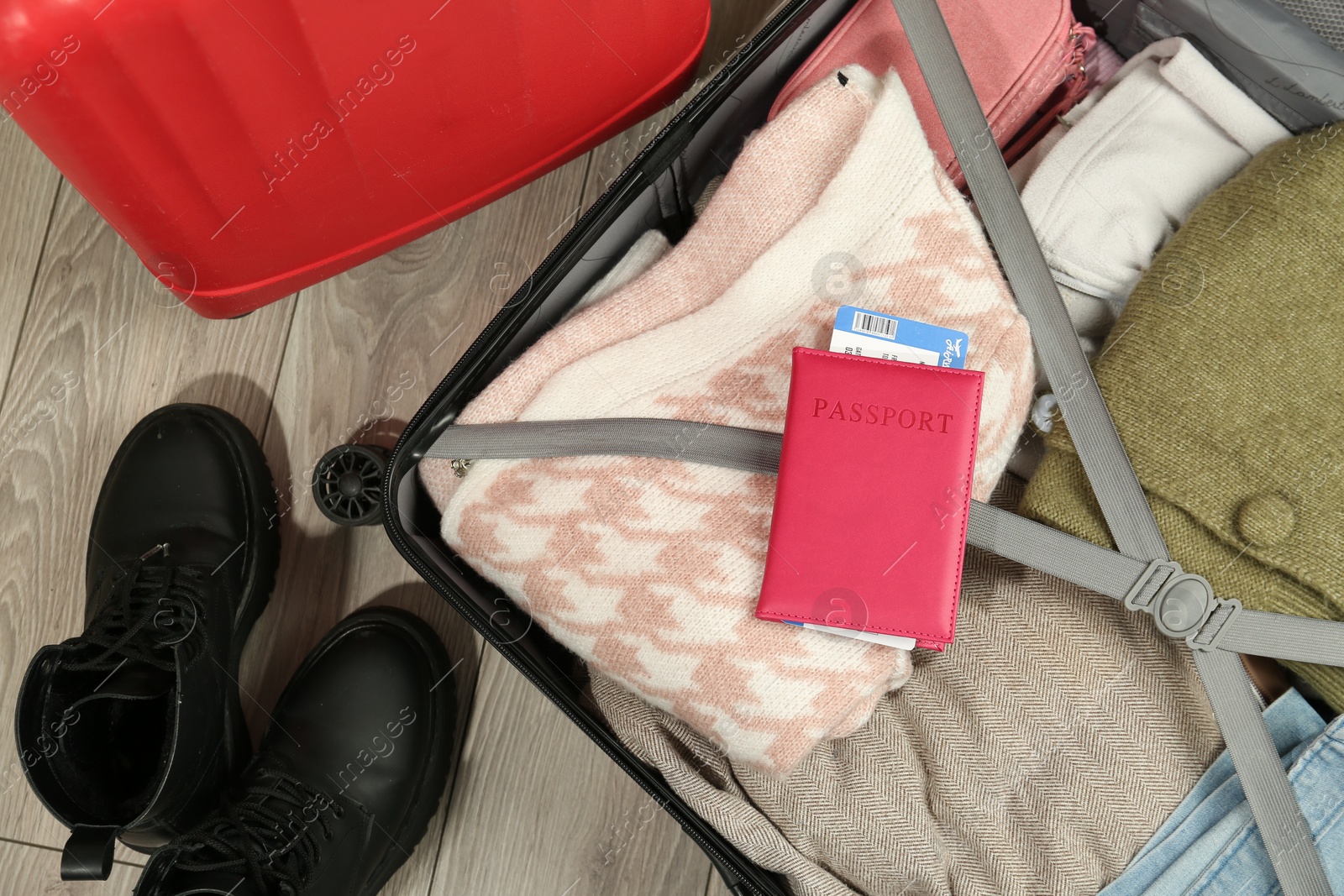 Photo of Passport with ticket on packed suitcase indoors, top view