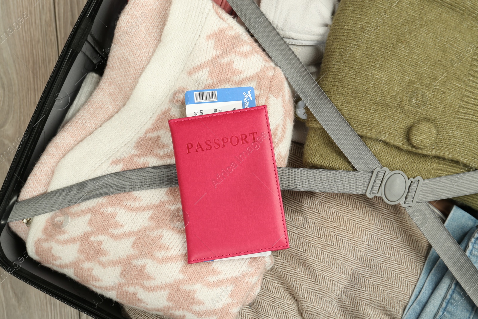 Photo of Passport with ticket on packed suitcase indoors, top view