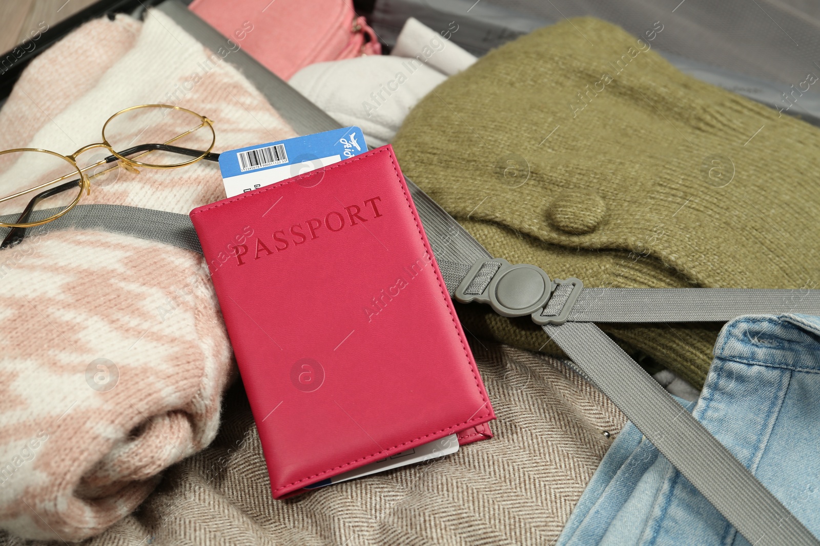 Photo of Passport with ticket on packed suitcase, closeup