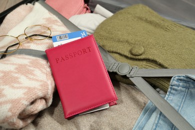 Photo of Passport with ticket on packed suitcase, closeup