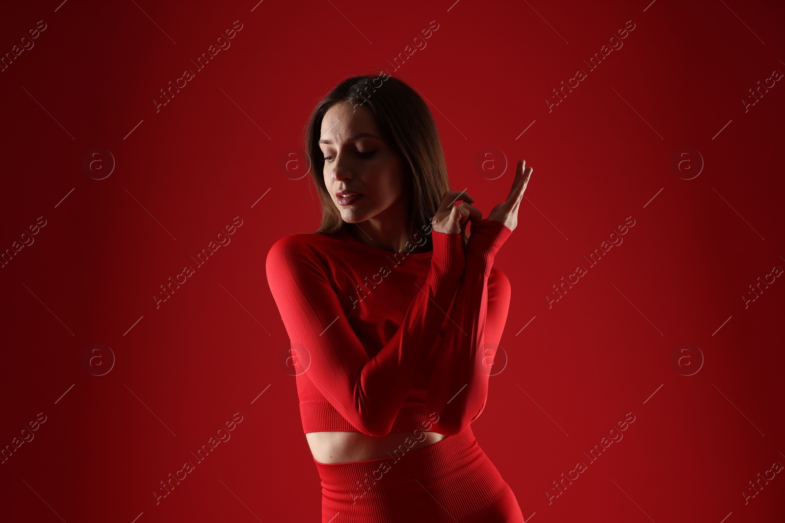 Photo of Beautiful woman in stylish sportswear on red background