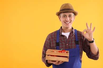 Photo of Farmer with vegetables showing okay gesture on orange background. Space for text