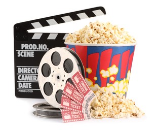 Tasty popcorn, movie tickets, clapper and film reels isolated on white