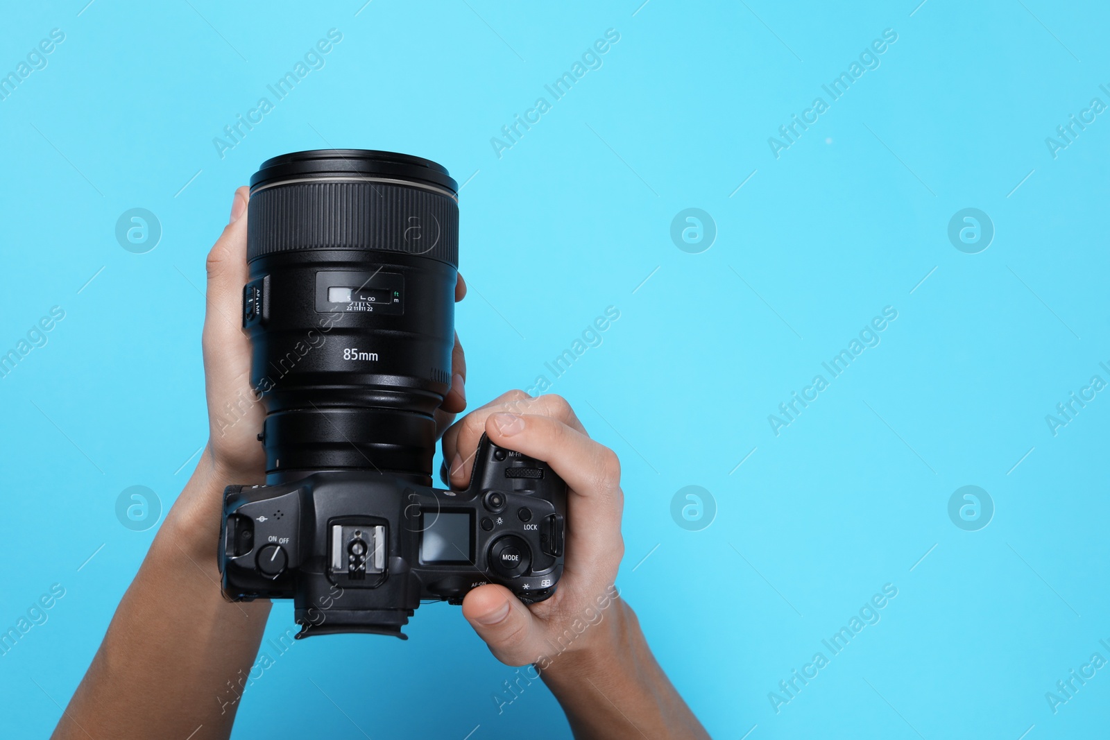 Photo of Photographer with professional camera on light blue background, top view. Space for text