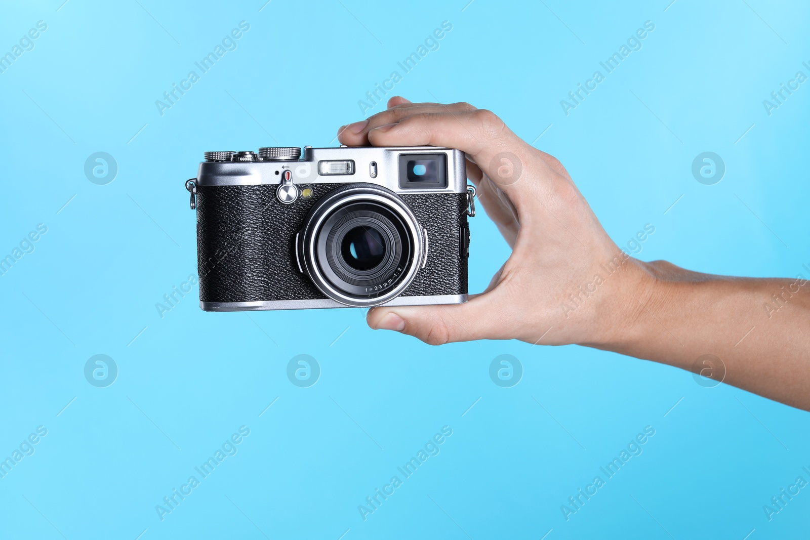 Photo of Photographer with vintage camera on light blue background, closeup