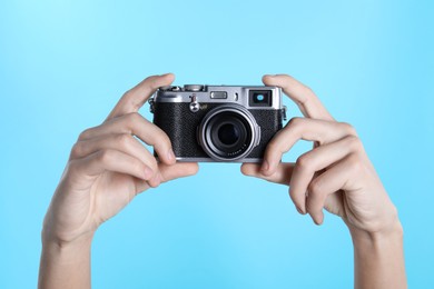 Photo of Photographer with vintage camera on light blue background, closeup