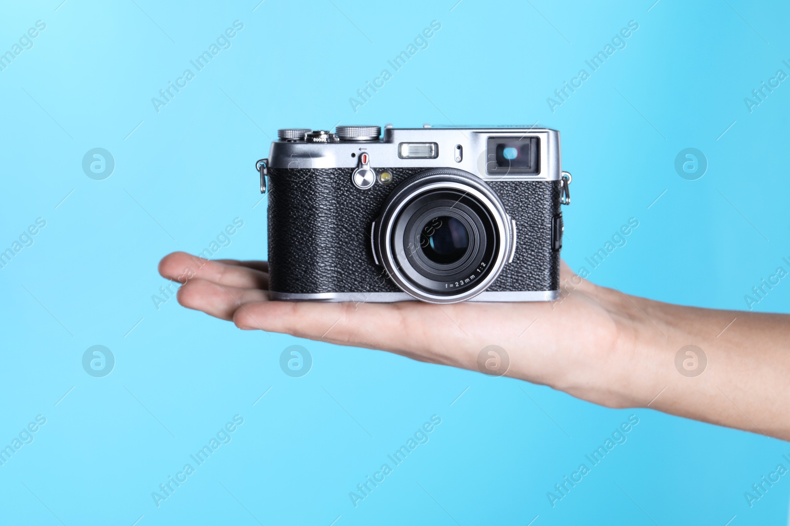 Photo of Photographer with vintage camera on light blue background, closeup