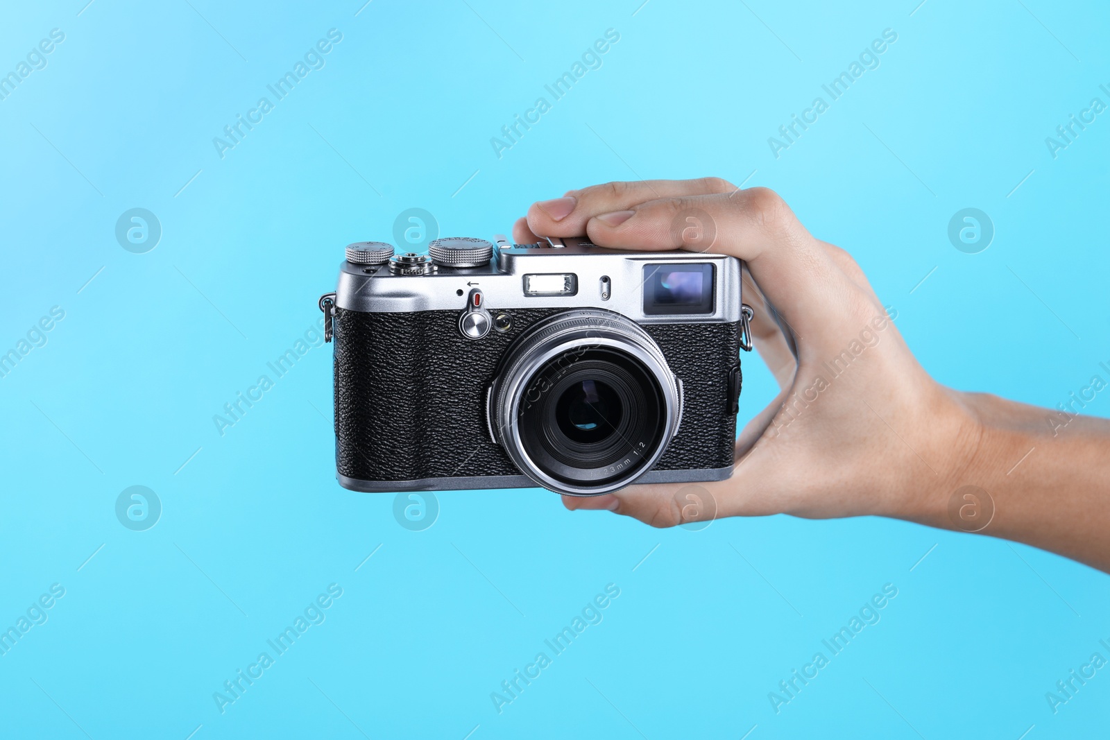 Photo of Photographer with vintage camera on light blue background, closeup