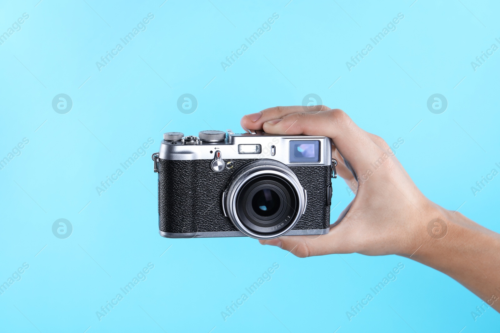 Photo of Photographer with vintage camera on light blue background, closeup