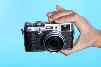 Photo of Photographer with vintage camera on light blue background, closeup