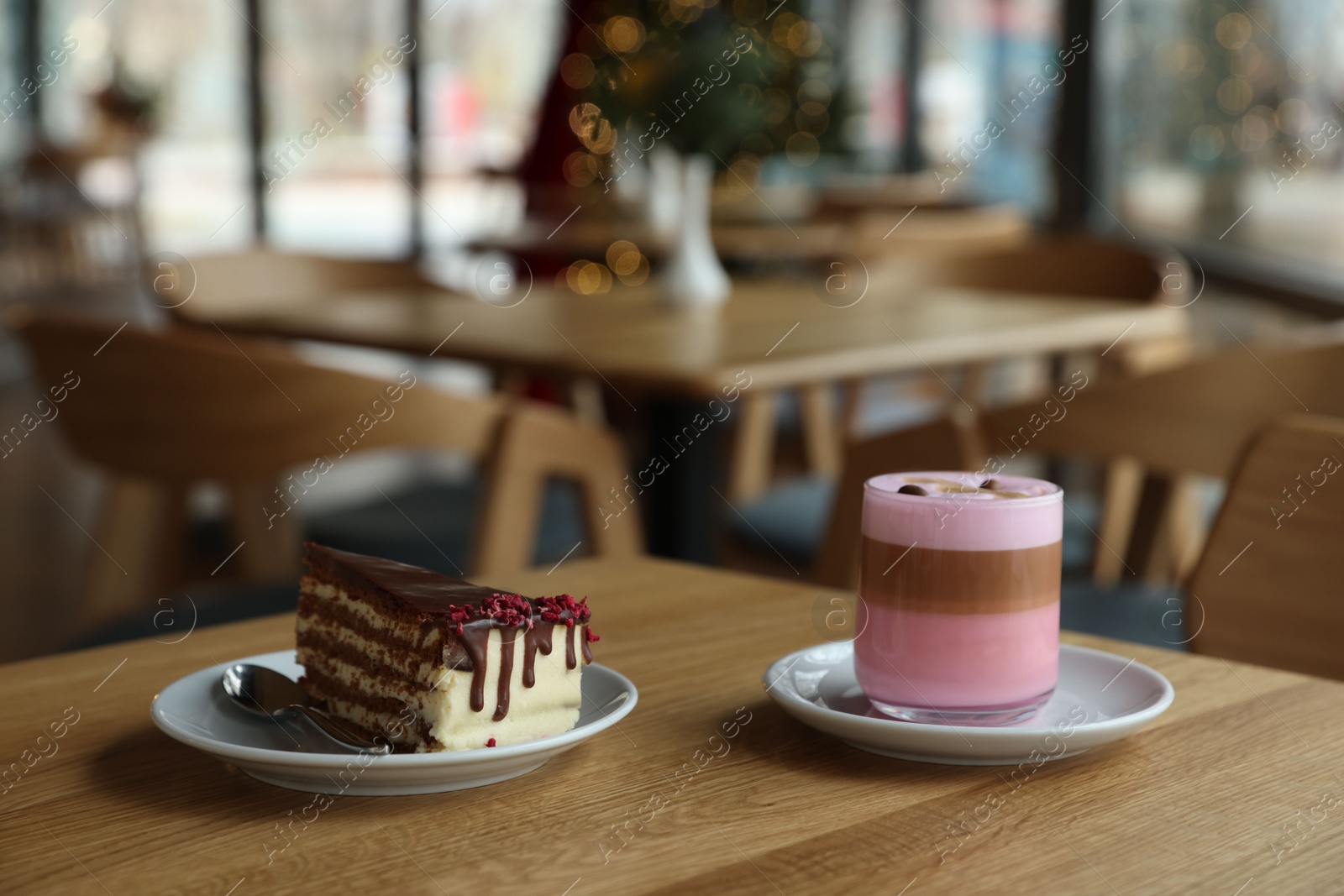 Photo of Delicious cake and pink latte served on wooden table in cafe