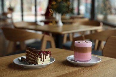 Photo of Delicious cake and pink latte served on wooden table in cafe