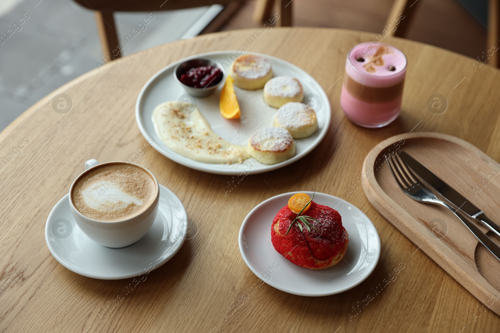 Photo of Delicious cottage cheese pancakes, dessert and coffee served on wooden table in cafe