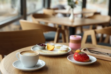 Photo of Delicious cottage cheese pancakes, dessert and coffee served on wooden table in cafe