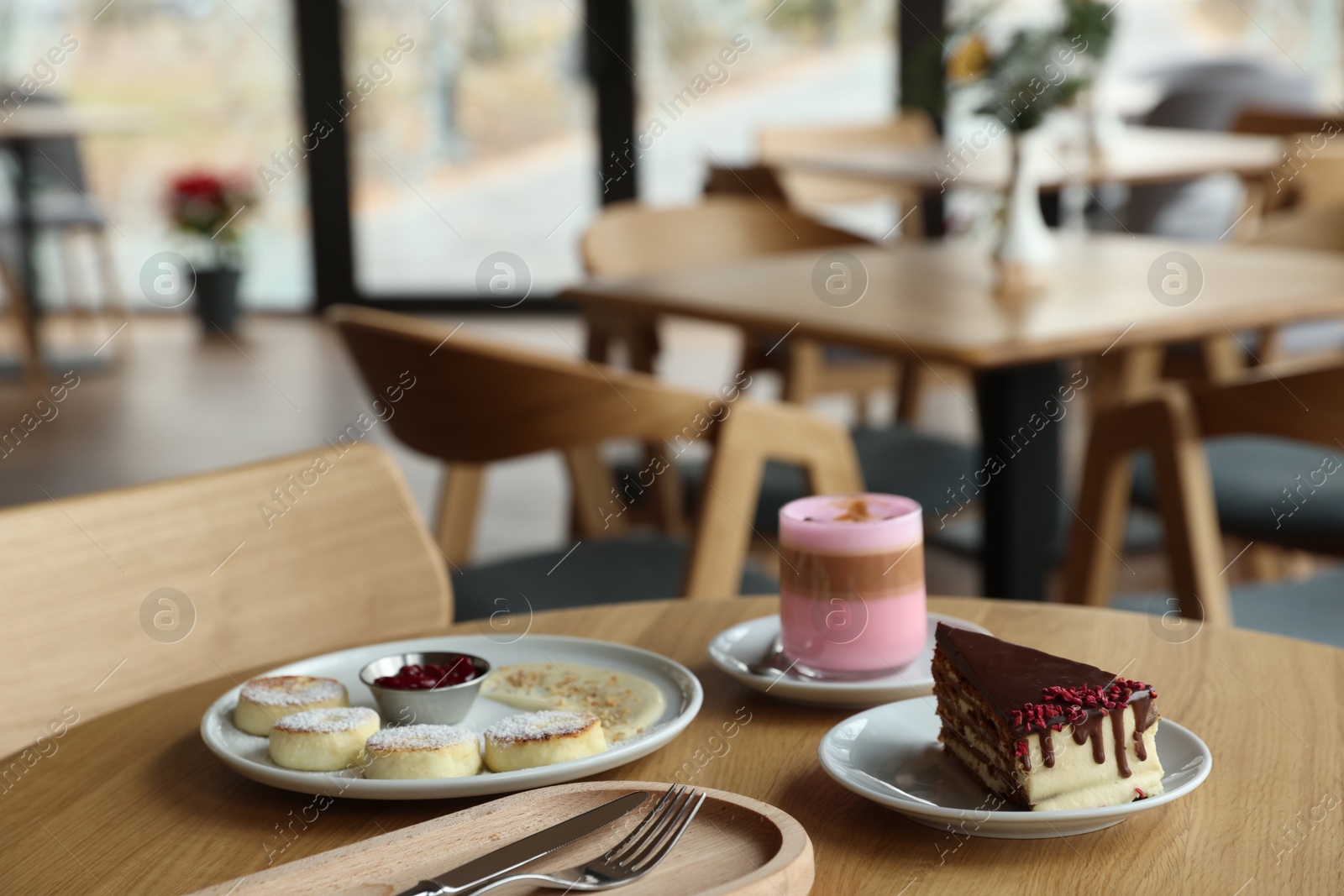 Photo of Delicious cottage cheese pancakes, cake and coffee served on wooden table in cafe