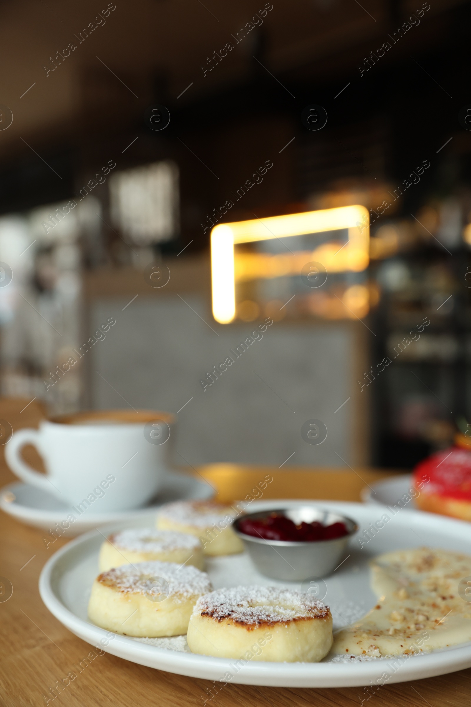 Photo of Delicious cottage cheese pancakes and coffee served on wooden table indoors