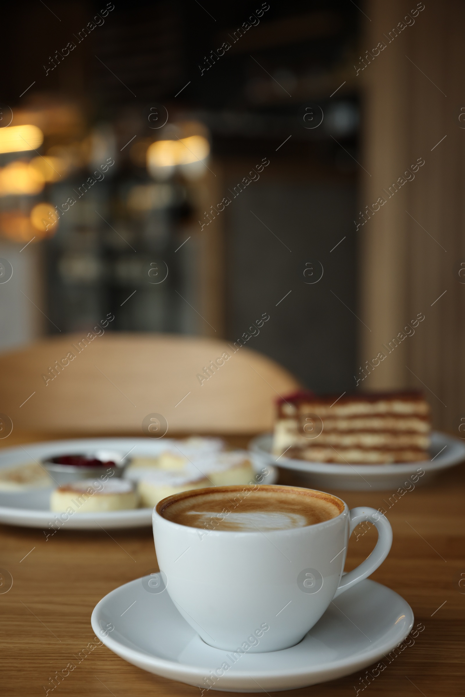 Photo of Aromatic coffee and delicious desserts served on wooden table in cafe, closeup