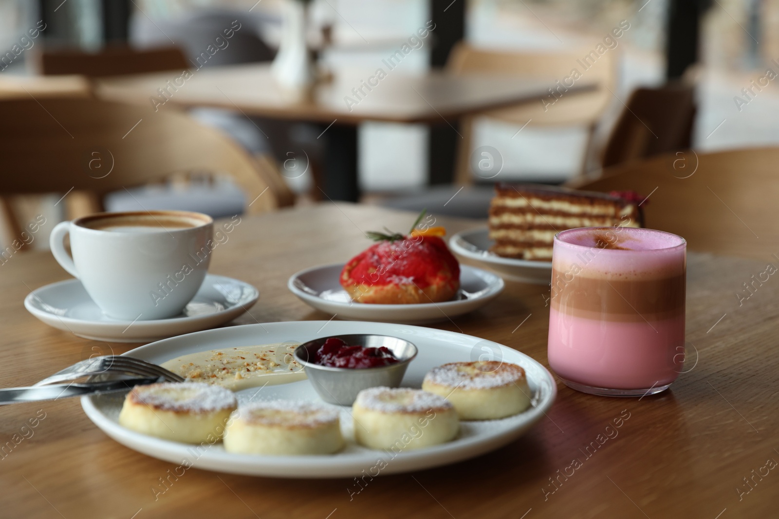 Photo of Delicious cottage cheese pancakes, desserts and aromatic coffee served on wooden table in cafe