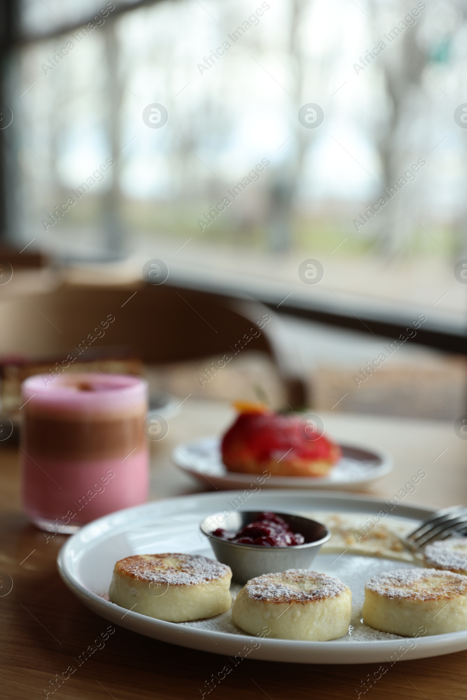 Photo of Delicious cottage cheese pancakes, desserts and aromatic coffee served on wooden table in cafe, closeup